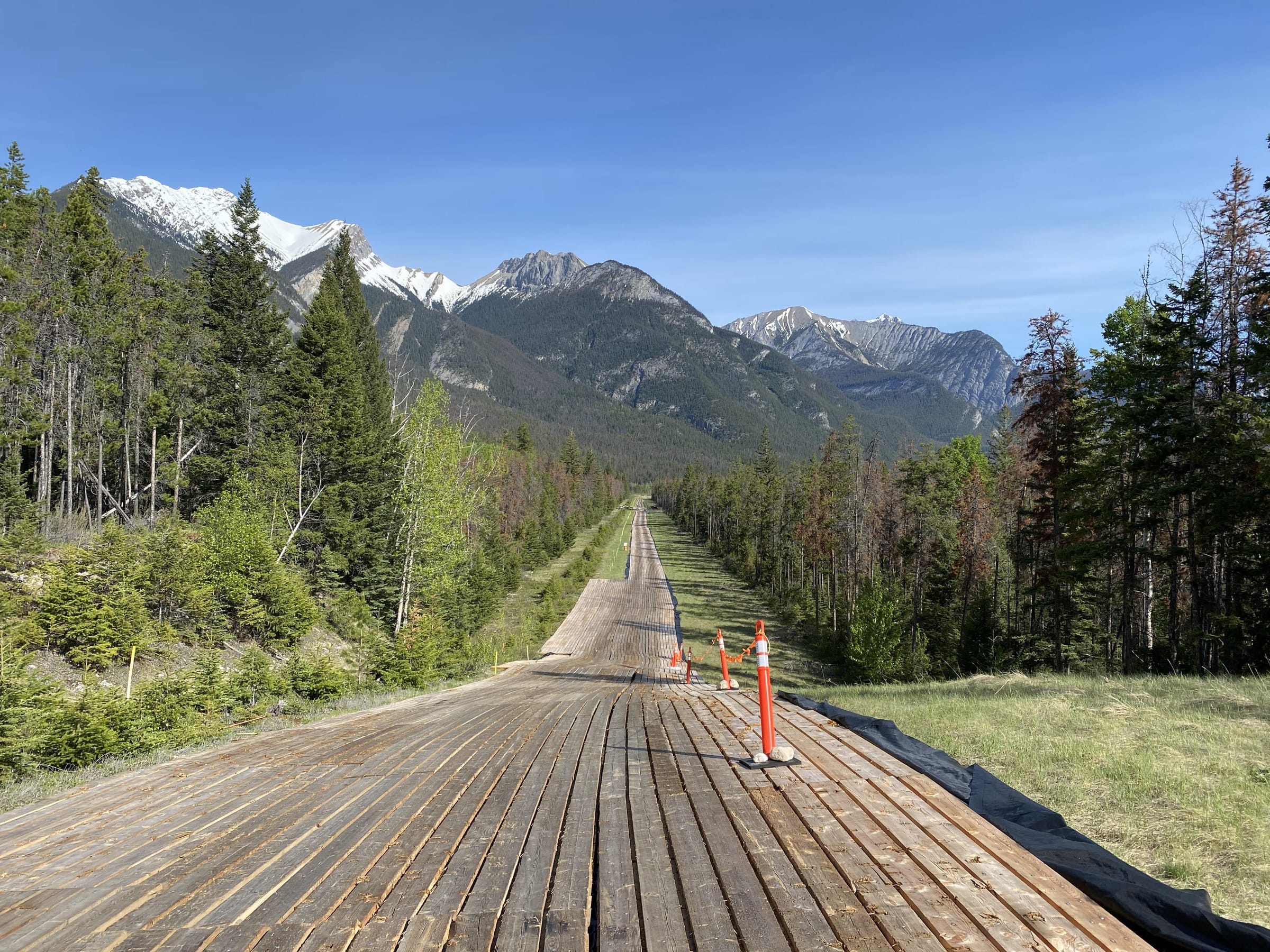An access-mat road laid across open ground with the Rocky Mountains behind, a Bear Valley Solutions and Centurion Matting project