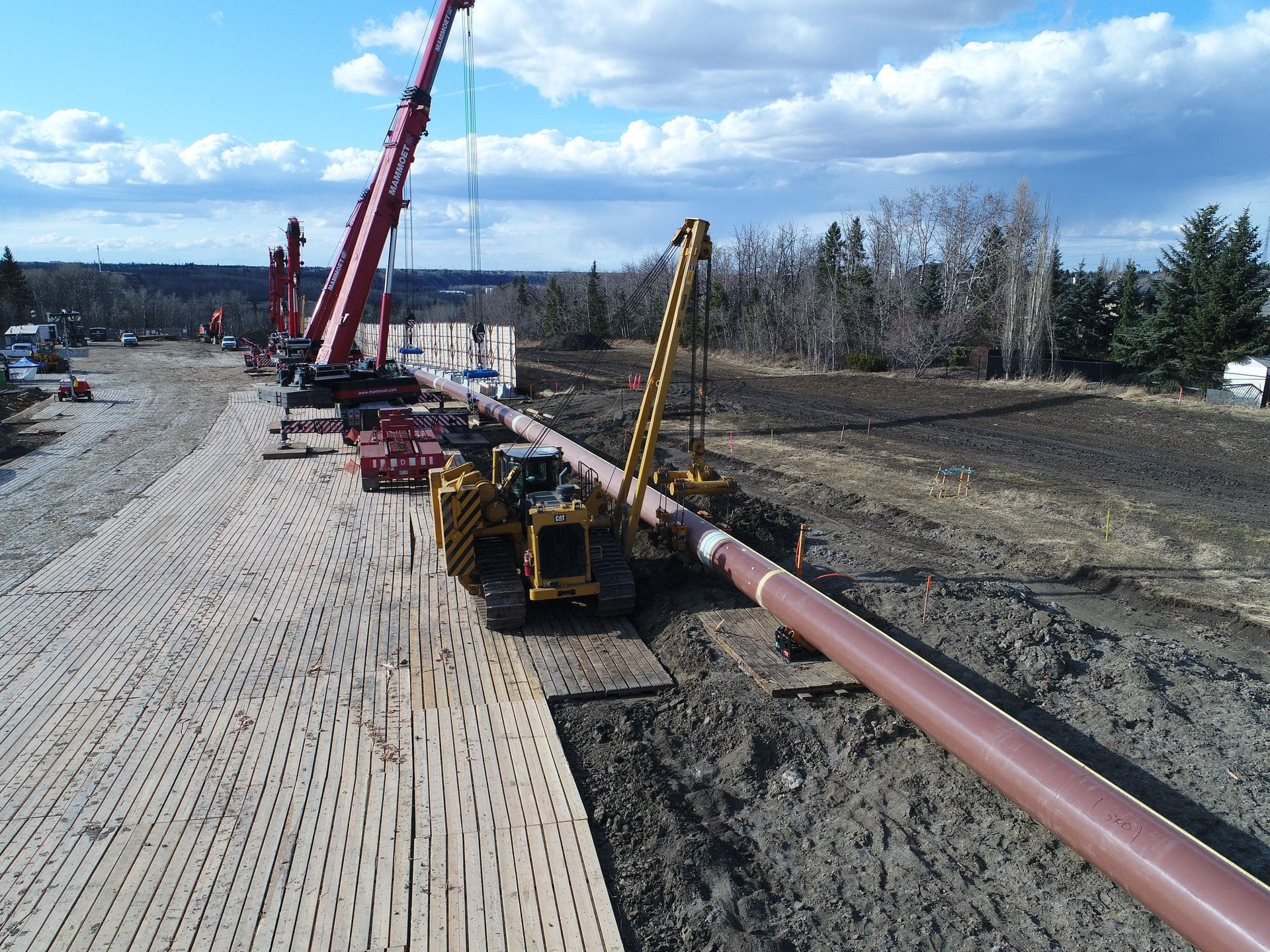 Pipeline construction crew and equipment working on a Centurion access-mat road